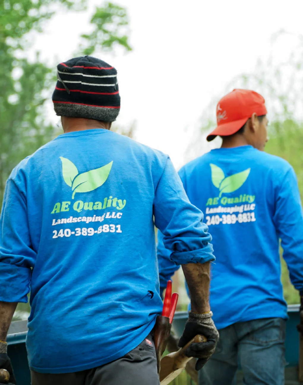 Two landscapers in AE Landscaping uniforms working