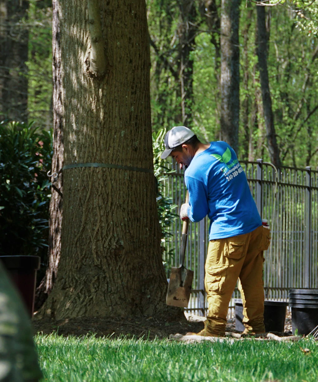 Worker in an AE Landscaping uniform working with a shovel