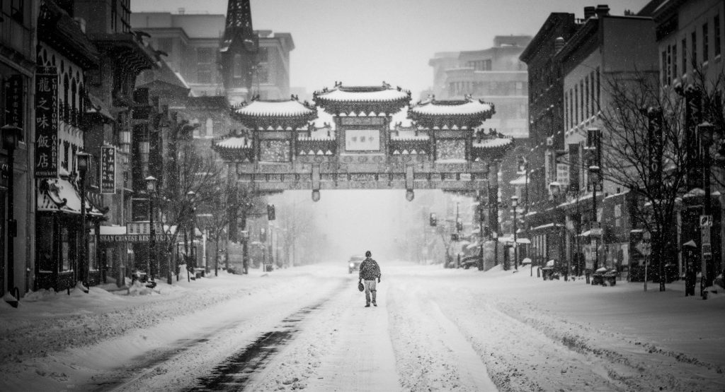 Person walking in the snow under DC's Chinatown Arch